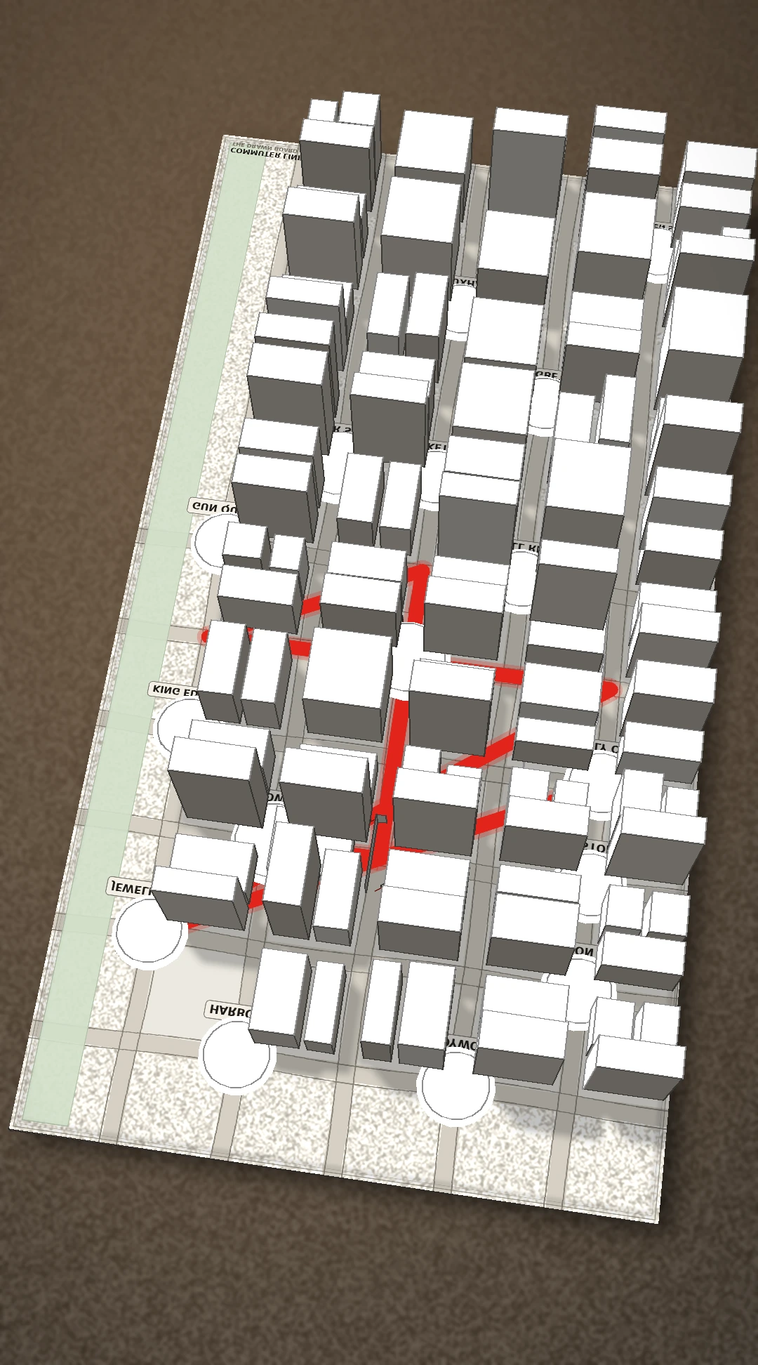 The Commuter Lines board as a paper atlas sheet lying on a desk, with buildings standing on the map and a red route running between them.